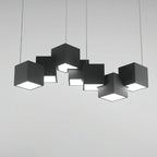 A Clérachic black cube chandelier on a light grey backdrop, shown straight on with the white undersides glowing.