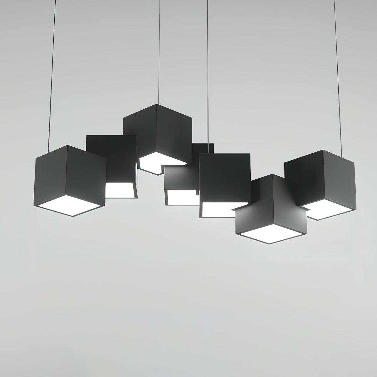 A Clérachic black cube chandelier on a light grey backdrop, shown straight on with the white undersides glowing.
