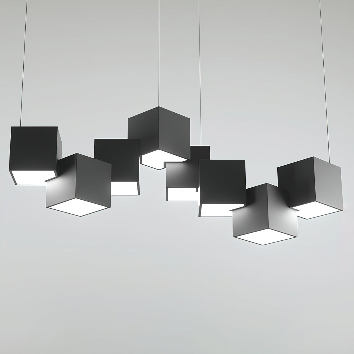 A Clérachic chandelier of black cubes on a light grey backdrop, in a wide row with a lit opening beneath each.