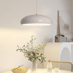 Pale grey Clérachic pendant glowing over a round table set with a vase of dried stems, a bowl of lemons and a cane-backed chair.