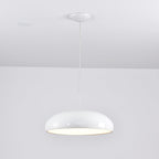 White Clérachic dome pendant glowing under its rim, hung from a white canopy beside a ceiling spotlight.