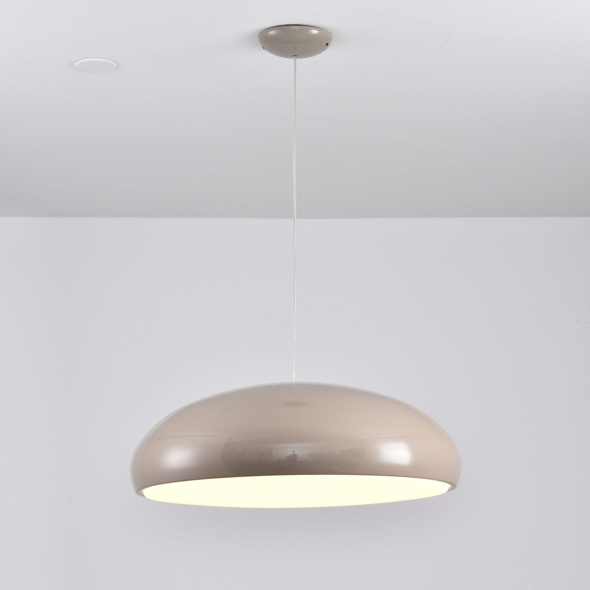 Warm grey Clérachic dome pendant lit from below, with a matching grey ceiling canopy and a glossy shell.