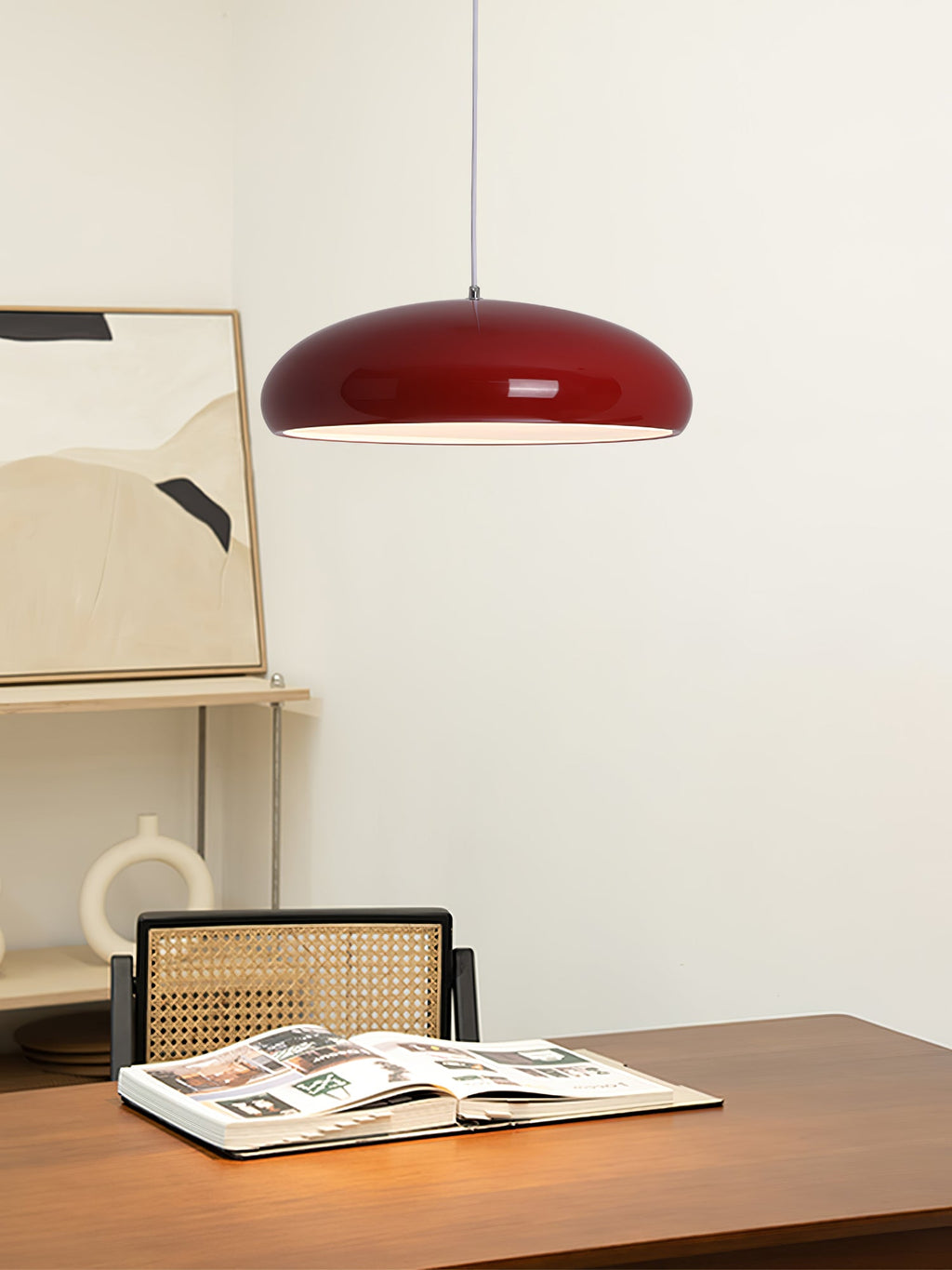 Dark-red Clérachic dome pendant over a walnut desk, with an open magazine, a cane chair and framed abstract art behind.