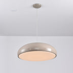 Warm grey Clérachic dome pendant lit from below, the diffuser glowing a soft peach inside its rim.