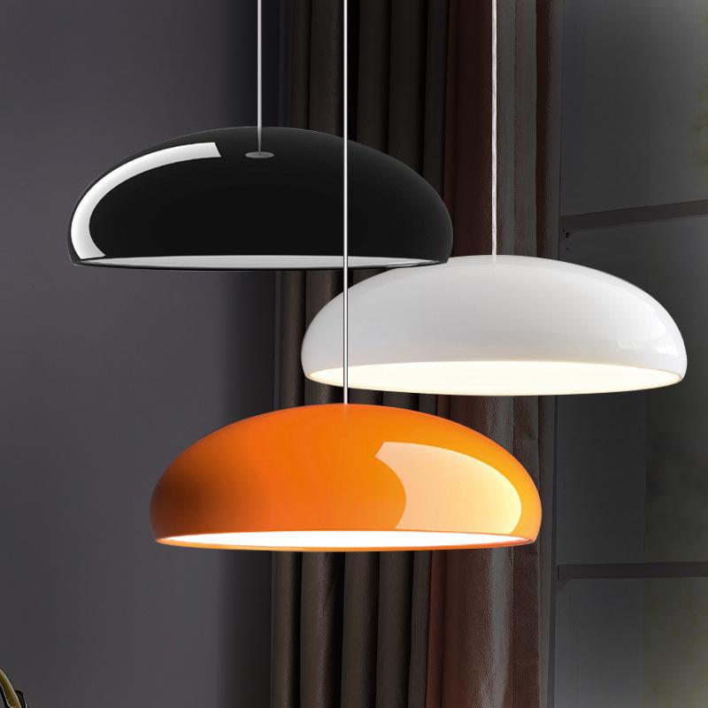 Three Clérachic dome pendants of different sizes hung together against dark curtains: one black, one white and one orange.