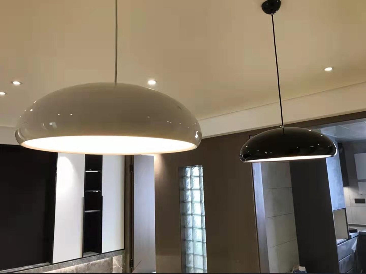 A pale grey Clérachic dome pendant in the foreground and a black one further back, hung from the ceiling of a modern interior.