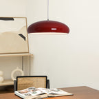 Dark-red Clérachic dome pendant above a walnut desk with an open magazine, a cane-backed chair and a ring-shaped vase.