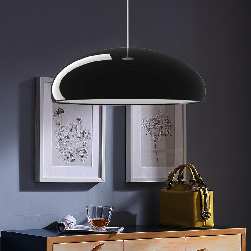 Black Clérachic dome pendant above a pale wood sideboard, with two framed botanical prints on a deep navy wall behind it.