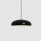 Close view of a black Clérachic dome pendant on grey, its glossy shell and warm white interior light both clear.