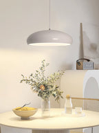 Light grey Clérachic dome pendant above a round table with dried flowers, a fruit bowl and a small vase against a cream wall.