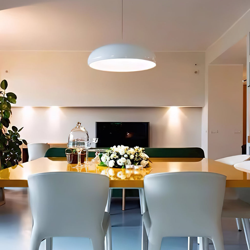 Pale Clérachic dome pendant hanging in a bright room, with a yellow dining table, white flowers and pale chairs below.