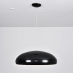 Wide, glossy black Clérachic dome pendant hung low from a black round canopy against a white wall.
