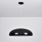 A black Clérachic dome pendant with a thin white rim of light below the shell, hung from a black ceiling canopy.