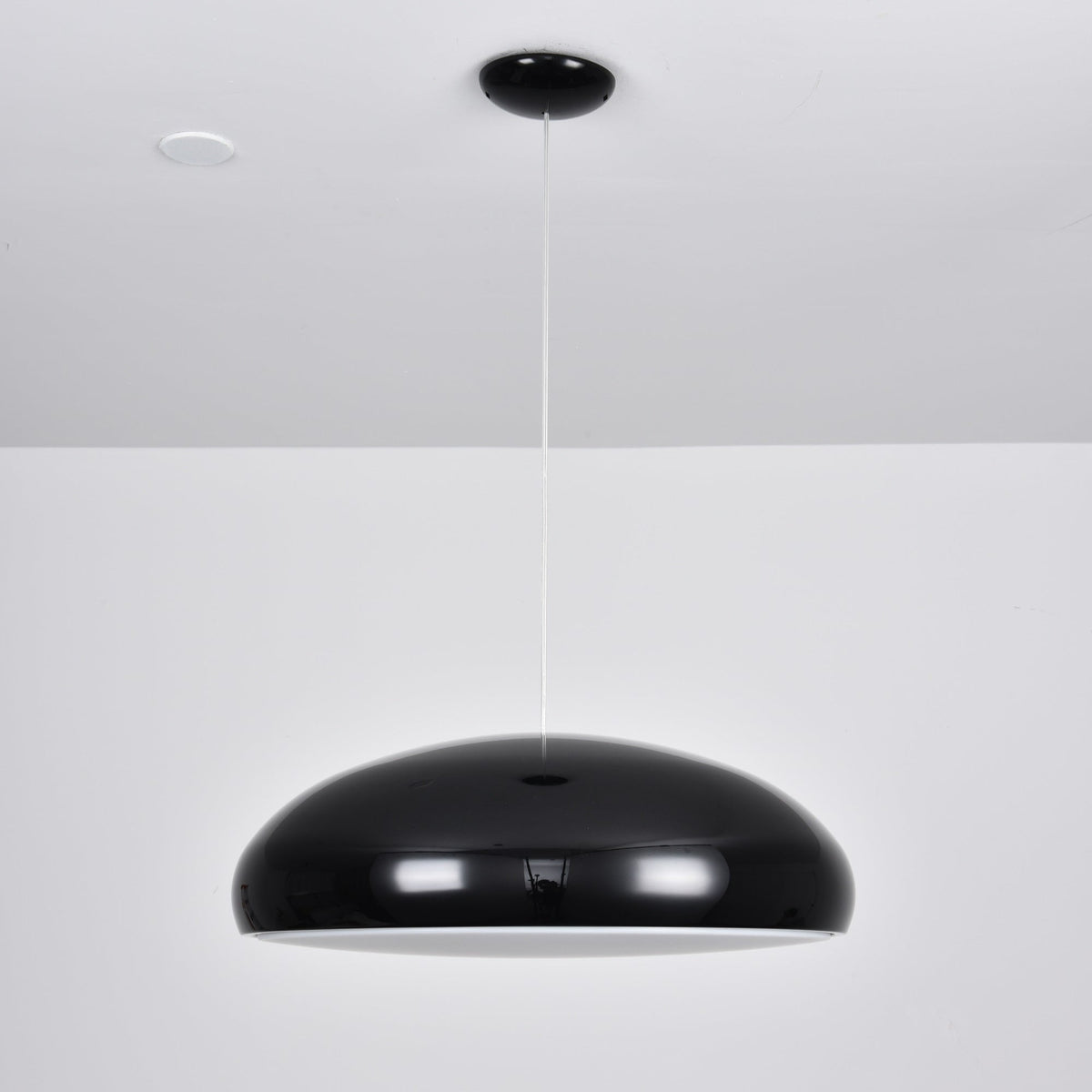 A black Clérachic dome pendant with a thin white rim of light below the shell, hung from a black ceiling canopy.