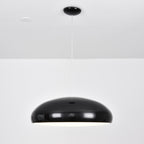 A black Clérachic dome pendant seen straight on, its shell glossy and its underside barely lit.