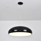 Black Clérachic dome pendant lit from below, with a bright warm diffuser visible under the shell.