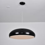 Black Clérachic dome pendant viewed slightly from beneath, with its pale diffuser disc glowing at a low level.