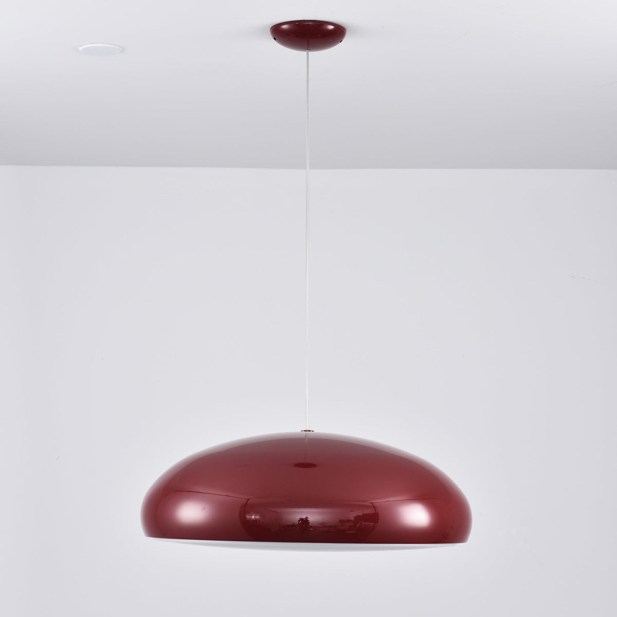 Dark-red Clérachic dome pendant on a long white cable, the shell reflecting the room, with a small red canopy above.