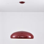 A dark-red Clérachic dome pendant at eye level, unlit, with a glossy shell and a fine white cable.