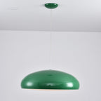 A green Clérachic dome pendant with a glossy shell and a faint warm light under the rim, hung by a thin white cable.