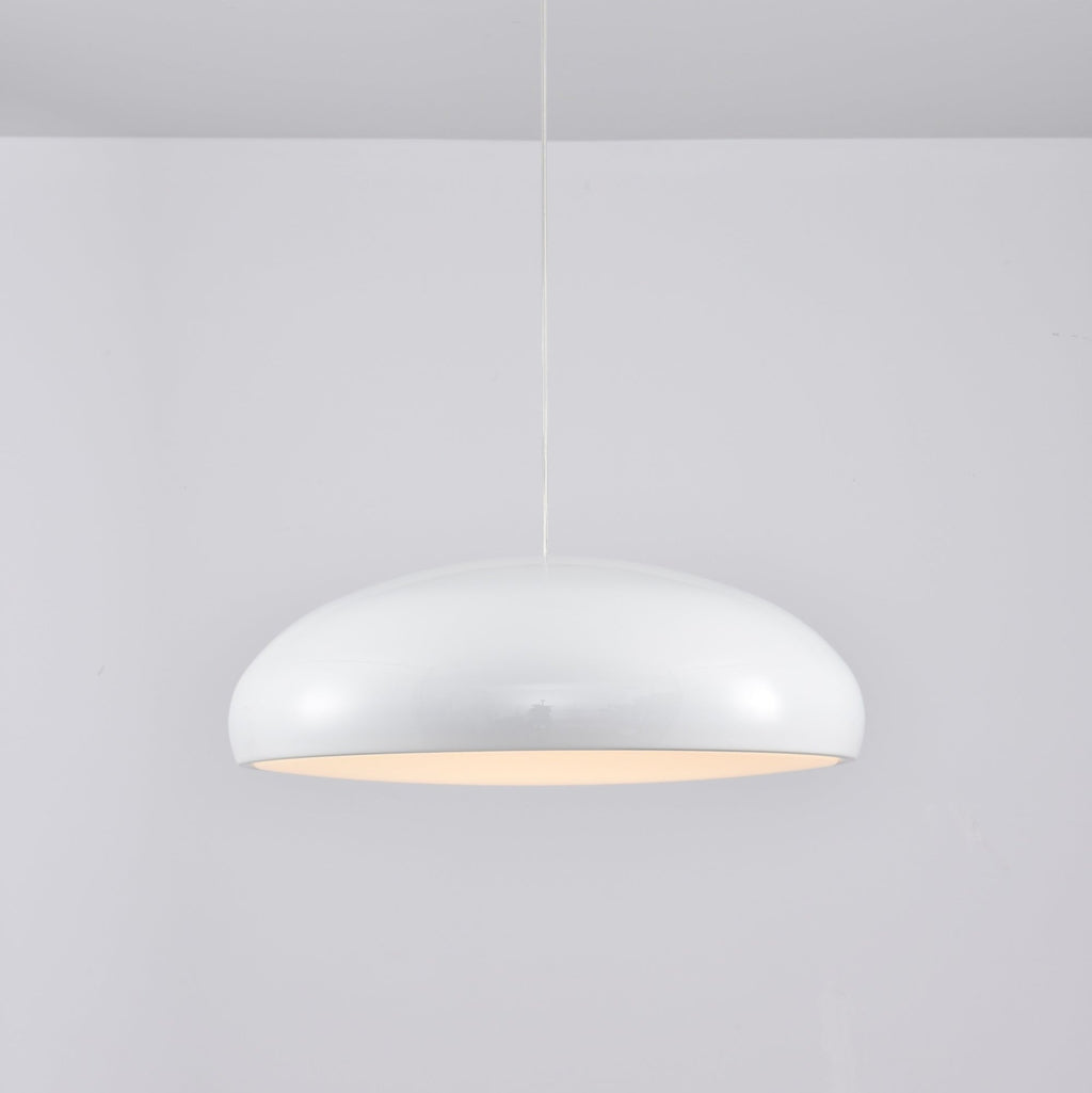 White Clérachic dome pendant with a warm peach glow at the rim, seen side-on against a pale wall.