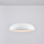 White Clérachic dome pendant with a warm peach glow at the rim, seen side-on against a pale wall.