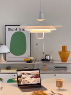 This white Clérachic pendant lights a table set with a laptop and a poster in the background, its lower tiers glowing.