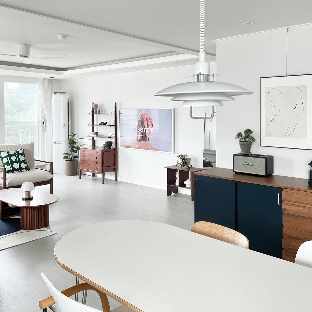 In an open-plan room with a long white table, a white Clérachic pendant hangs from a white coiled cable.