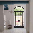 A small white Clérachic pendant hangs in a hallway, in front of an arched black glazed door and a plaster bust.