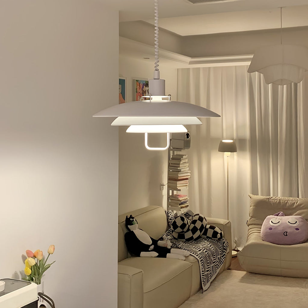 Lit from within, a white Clérachic pendant hangs in a corner above a sofa with patterned cushions and floor-length curtains.