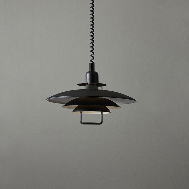 Black Clérachic pendant against a mid-grey backdrop, with a white inner edge on each shade and a metal handle below.