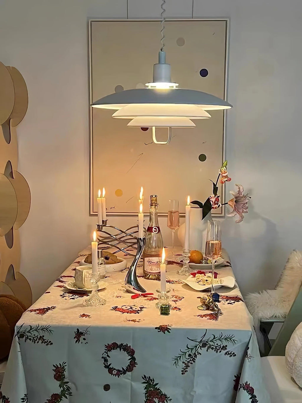 Over a dining table laid with candles and a floral cloth, a white Clérachic pendant gives a soft, warm light.