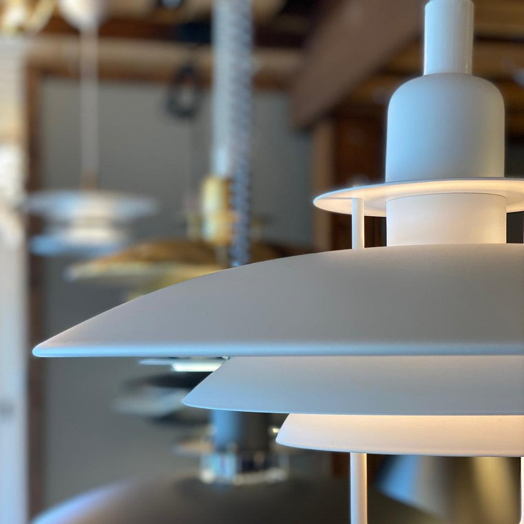 Extreme close view of the stacked white shades and collar on this Clérachic pendant, with the room softly blurred.
