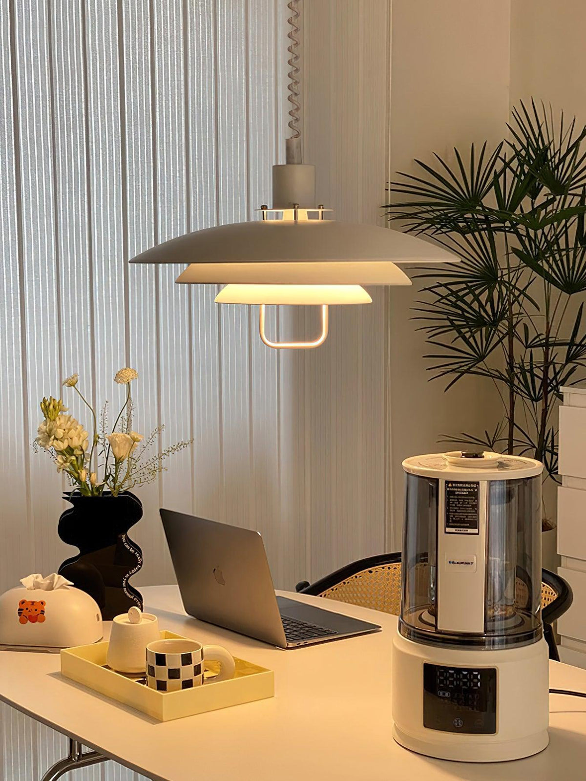 Another angle of a white Clérachic pendant over a laptop desk with a tray and a vase of dried flowers.