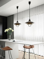 Two black Clérachic pendants with warm metallic inner shades hang over a white kitchen island with leather stools.