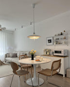 A white Clérachic pendant hangs in the centre of a compact living and dining space with a tulip-style table.