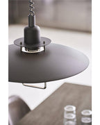 Close-up of the black collar and wide top shade on this Clérachic pendant, with a table blurred below.