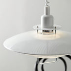 Close view of the glossy white top shade and the clear collar around the bulb on this Clérachic pendant.