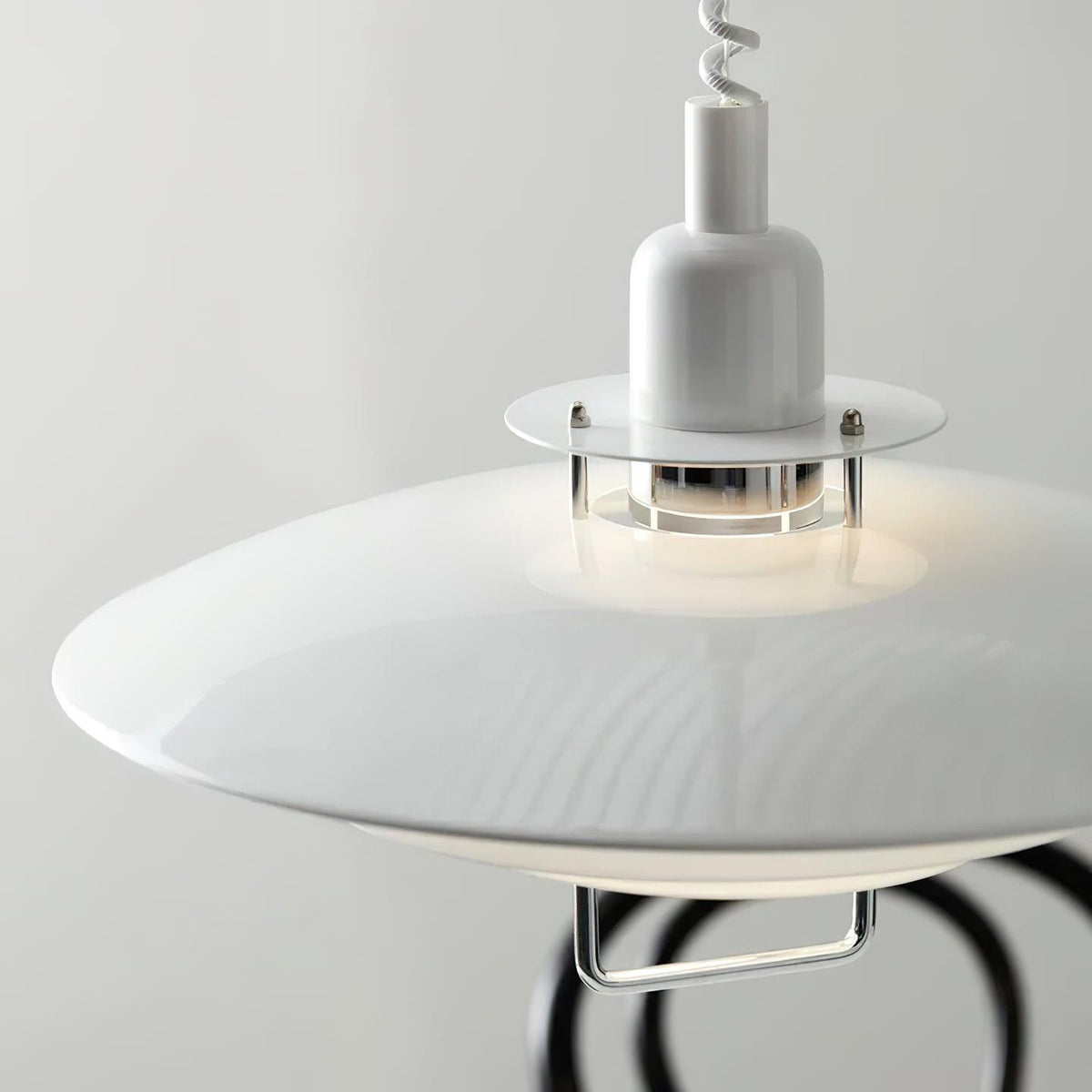 Close view of the glossy white top shade and the clear collar around the bulb on this Clérachic pendant.