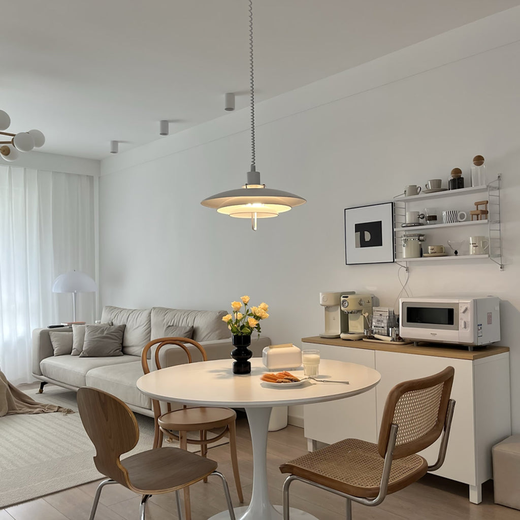 A wider shot of a living room where a white Clérachic pendant hangs over a round table with yellow flowers.