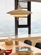A white Clérachic pendant, lit warm, hangs by a tall window with a hazy view, above a table set for a hot pot meal.