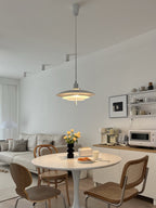 Seen from across the room, a Clérachic pendant hangs over a round table with cane chairs and open shelves.
