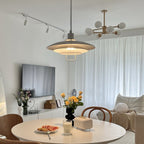 A nearer view of the same room, with a grey-and-white Clérachic pendant glowing over a table of citrus and flowers.