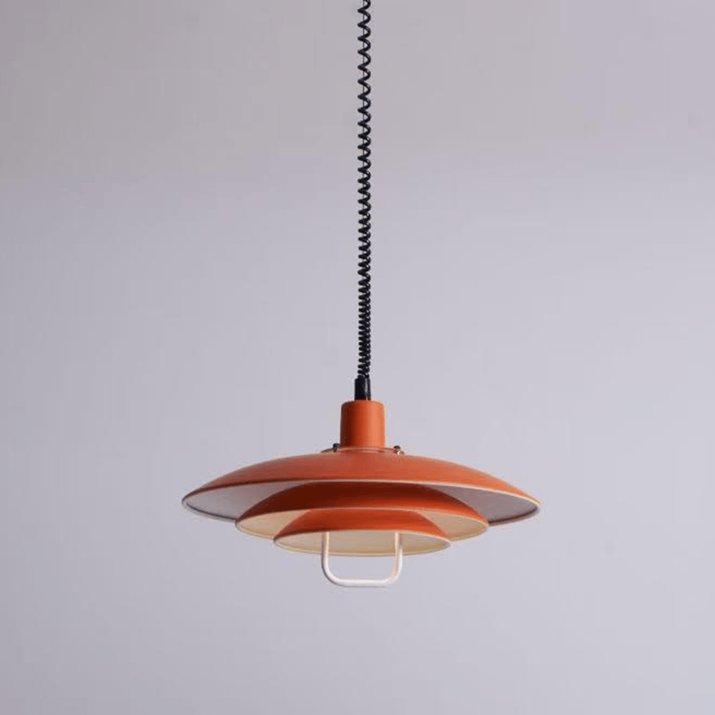 An orange Clérachic pendant on a lilac-grey backdrop, the lower tiers showing a pale interior.