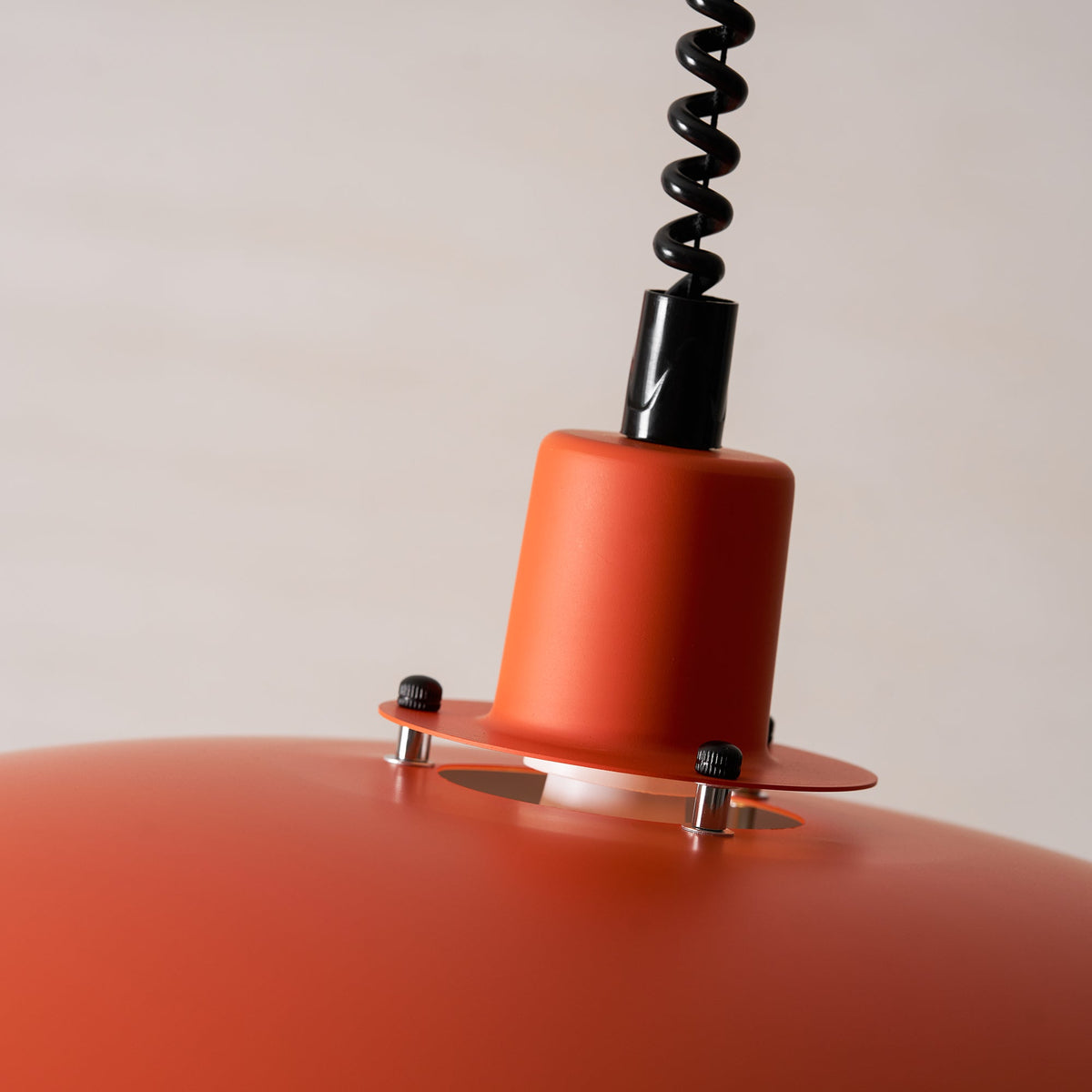Close view of the orange collar, bolted ring and black coiled cable at the top of this Clérachic pendant.