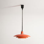 Orange Clérachic pendant hung on its full cable drop from a black ceiling cup, against a plain white wall.