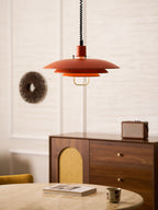 Orange Clérachic pendant beside a wall piece, with a walnut sideboard and a stone table with a book and cup.