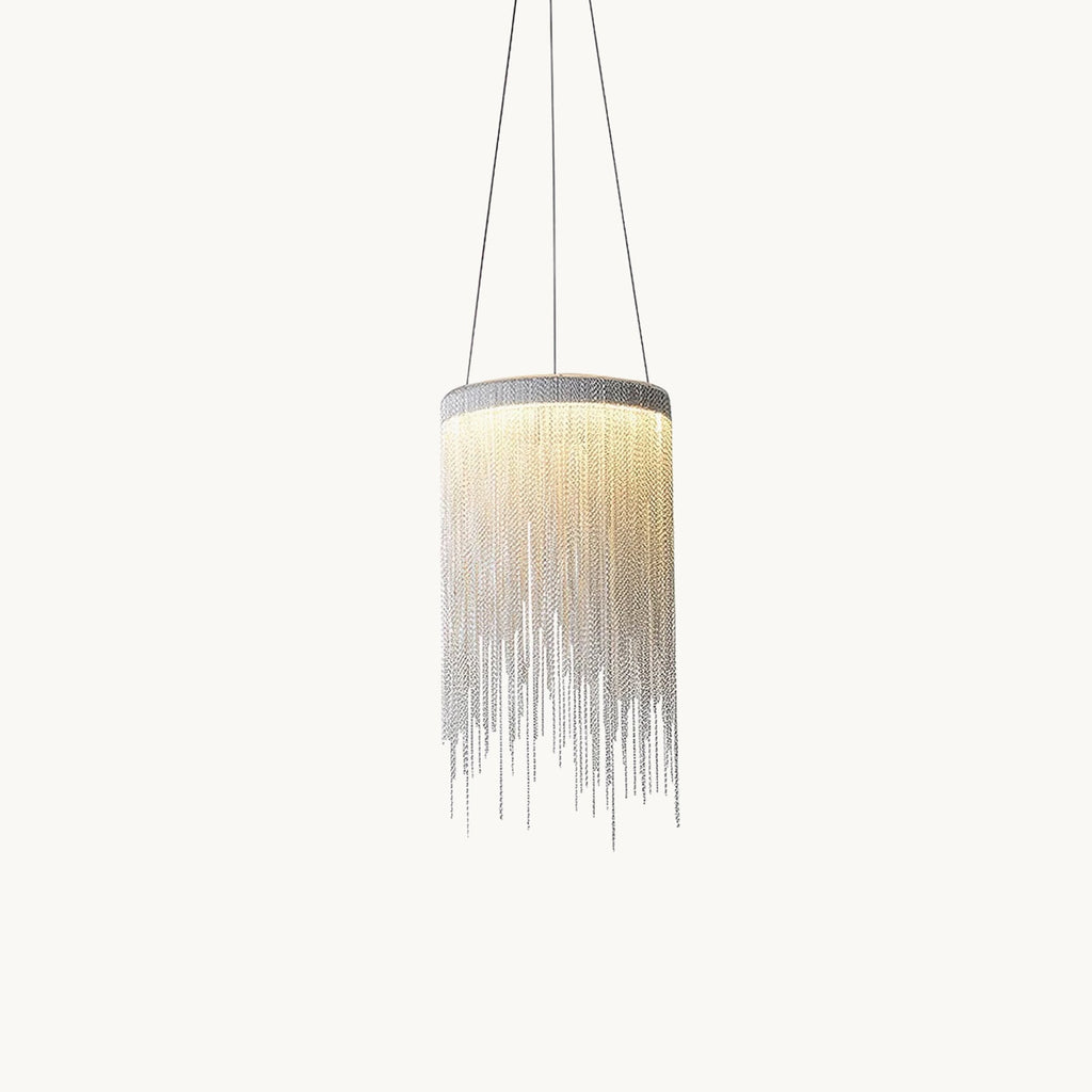 Lit Clérachic pendant with a cylinder of fine silver chains hanging on three thin cords against a plain off-white backdrop.
