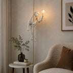 White resin monkey on a thick rope, lit with a warm filament bulb, above a boucle armchair and marble side table; a Clérachic pendant.