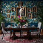White monkey pendant seen high above a dark dining table, against a deep blue wall of tropical wallpaper and gilt-framed pictures; a Clérachic piece.